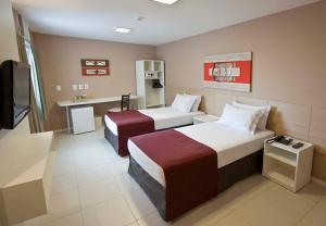 een hotelkamer met 2 bedden en een televisie bij Grande Hotel Itaguaí in Itaguaí