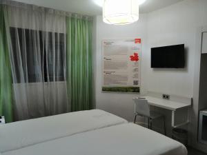 een slaapkamer met een bed, een bureau en een televisie bij Ibis Styles Madrid Prado in Madrid