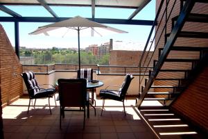 uma varanda com uma mesa e cadeiras e um guarda-sol em Apartamentos Cinco Rosas em Madrid