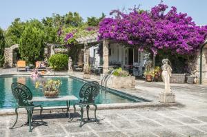 a pool with a table and chairs and purple flowers at Hotel Rural Biniarroca - Adults Only in Sant Lluis