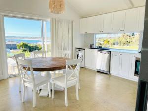 a kitchen with a table and chairs and a kitchen with a view at Magnolia in Emu Bay