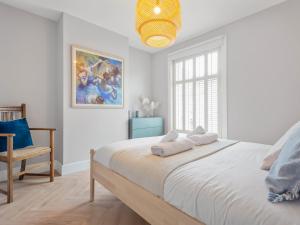 a white bedroom with a large bed and a chair at Pass the Keys 3 bed Scandi Heaven minutes from the beach in Whitstable