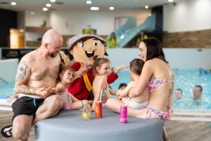 a group of people sitting next to a swimming pool at Atrium Hotel - Family friendly in Nový Smokovec