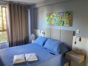 1 dormitorio con 1 cama azul y 2 toallas en Frente Mar - Duas Suítes no C.Branco, en João Pessoa