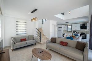 a living room with two couches and a table at Modern chic 4-bedroom villa with private pool and garden in central Hisaronu in Fethiye