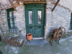 una puerta verde de un edificio con una olla y una rueda en Sklithro's stonehouse, en Sklíthron