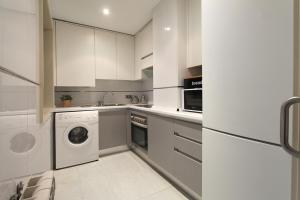 a kitchen with white cabinets and a washer and dryer at Apartamentos Cinco Rosas in Madrid