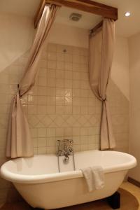 a white bath tub in a bathroom with a curtain at Chateau de Forges in Concremiers