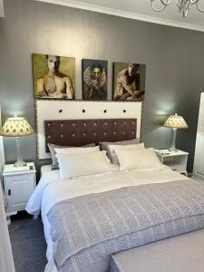 a bedroom with a bed with three paintings on the wall at Somerset West Garden Apartments 1 in Somerset West