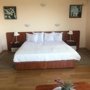 a bedroom with a bed with white sheets and two lamps at Guest House Golden Flake 4km from Bolata beach in Bŭlgarevo
