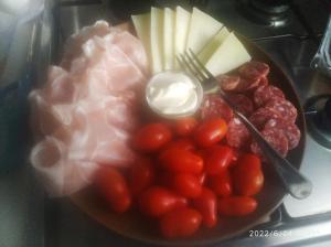 une assiette de nourriture avec des tomates, du fromage et de la viande dans l'établissement B&B Stella Maris, à Magomadas
