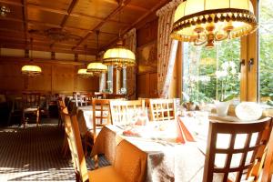 a dining room with tables and chairs and chandeliers at Pension Göbel in Willingen