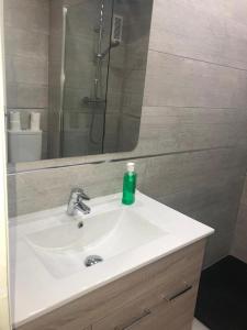 un lavabo con una botella de jabón verde. en Apto EN JARDINES DEL PUERTO, en Marbella