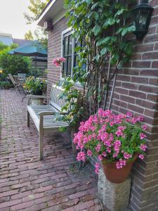 a bench sitting on a brick patio with pink flowers at B&B Het Gasthuys in Amerongen