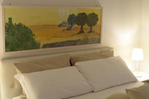 a painting above a white couch with two pillows at BORGANTHIA in Alberobello