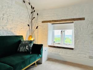 a living room with a green couch and a window at The Stables - Luxury Holiday Cottage in Welsh Newton Common