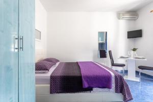 a bedroom with a purple bed and a glass door at Apartments Dobrila in Hvar
