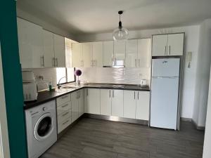 ロス・クリスティアーノスにあるCORNELIA´S HOME 7 Exelente ubicacionのキッチン(白いキャビネット、洗濯機、乾燥機付)
