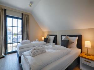 zwei Betten in einem Hotelzimmer mit Fenster in der Unterkunft Reetland am Meer - Luxus Reetdachvilla mit 3 Schlafzimmern, Sauna und Kamin F18 in Dranske + 16 Fotos