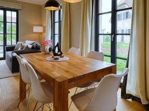 a dining room with a wooden table and white chairs at Reetland am Meer - Superior Reetdachvilla mit 2 Schlafzimmern F25 in Dranske
