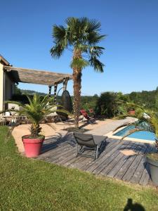 a wooden deck with a chair and palm trees at Chambres d’hôtes in Saint-Aulaire