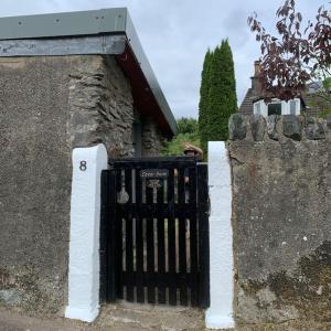 a gate in a stone wall next to a building at Cedarbank’s - 'Little Art House' in Kirn