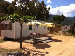 una casa con dos sombrillas, una mesa y sillas en Mobile Home A Saliva, en Peri