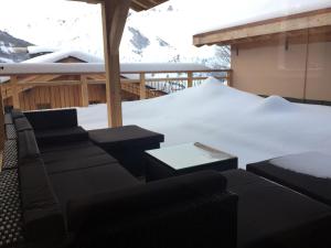 un patio coperto di neve con un divano e un tavolo di Chalet cosy accès pistes, sauna, cheminée, Wifi, parking - FR-1-344-411 a Saint-Martin-de-Belleville