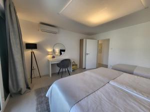een witte slaapkamer met een bed en een bureau bij Modern Apartment Tara with Parking in Malinska