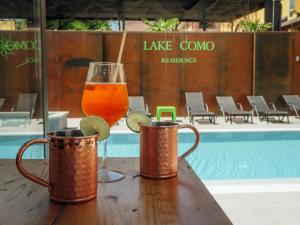 a drink and two mugs on a table next to a pool at Residence Lake Como in Colico
