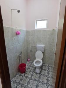 a bathroom with a toilet and a red bucket at Homestay Che Naa in Kuantan
