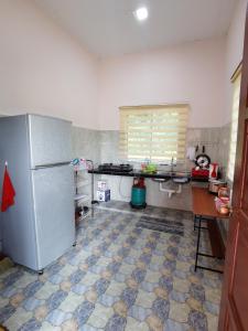 a kitchen with a refrigerator and a tiled floor at Homestay Che Naa in Kuantan