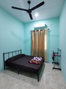 a bedroom with a bed with a ceiling fan at Homestay Che Naa in Kuantan