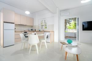 uma cozinha branca com cadeiras brancas e uma mesa em COSTA VASIA Seaside Suites and Apartments em Vrachati