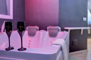 two wine glasses sitting on a table in a bathroom at Capri Spa Hotel in Casoria