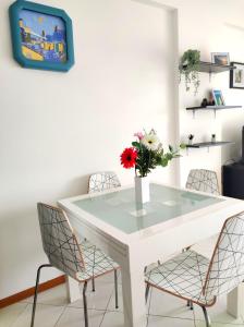 a white dining room table with chairs and a vase of flowers at Bellavista apartment Letojanni in Letojanni