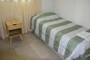a bed with a green and white blanket next to a nightstand at El Mirador in Potrerillos