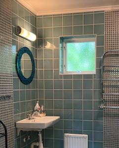 baño de azulejos verdes con lavabo y ventana en Grönelid Gård en Tived