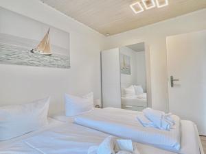 twee bedden in een kamer met een zeilboot in de spiegel bij Sonnensteg 5 - Ein Tag am Meer in Ostseebad Sellin