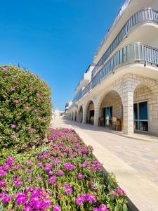 un edificio con fiori viola di fronte di Hotel Buenavista Beach House Trogir a Trogir