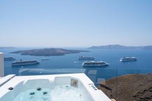 d'une baignoire avec vue sur l'eau et les bateaux. dans l'établissement Kratiras View Luxury Suites, à Fira