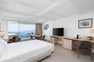 Habitación de hotel con cama y escritorio con TV. en Kratiras View Luxury Suites en Fira