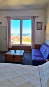 1 dormitorio con cama, sofá y ventana grande en Hostal El Mesón en Punta Arenas