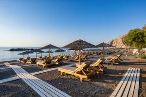 a bunch of chairs and umbrellas on a beach at Nissia Beach Apartments & Suites in Kamari