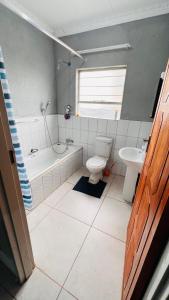 a bathroom with a tub and a toilet and a sink at Zinathi Lodge in Lebowakgomo +19 photos
