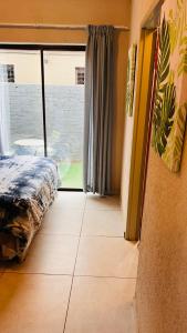 a bedroom with a bed and a large window at Zinathi Lodge in Lebowakgomo