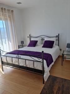een slaapkamer met een groot bed met paarse kussens bij Florindo - Lafões Guest House in Oliveira de Frades