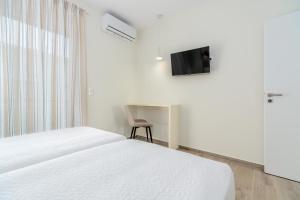 um quarto com uma cama, uma secretária e uma televisão em COSTA VASIA Boutique Apartments em Vrachati