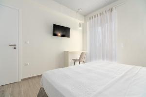 um quarto branco com uma cama e uma cadeira em COSTA VASIA Boutique Apartments em Vrachati