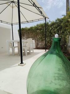 ポルト・チェザーレオにあるPoggio Fioritoの傘を置いたテーブルの横に座る緑のガラスの花瓶